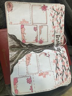 a binder with pink flowers on it sitting on top of a chair next to a book