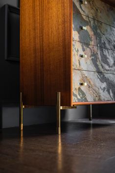 a wooden dresser sitting on top of a hard wood floor next to a black wall