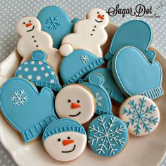 decorated cookies in the shape of snowmen and mittens are on a white plate