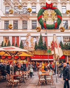 an outdoor christmas market with lots of tables and umbrellas in front of the building