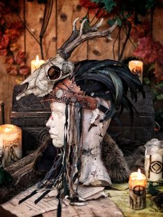 a man with horns and feathers on his head sitting in front of some burning candles