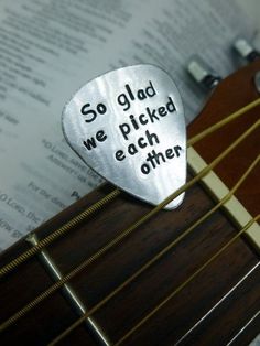 a guitar pick with the words so glad we picked each other on top of it