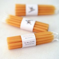 three orange candles with labels on them sitting next to each other