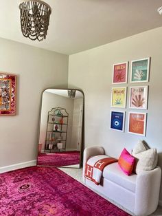 a living room filled with furniture and pictures on the wall next to a mirror in front of a doorway