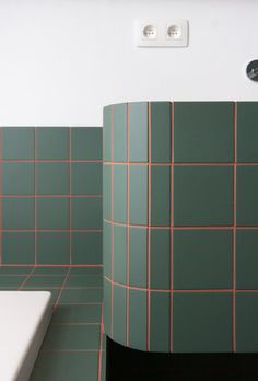 a bathroom with green and pink tiles on the walls