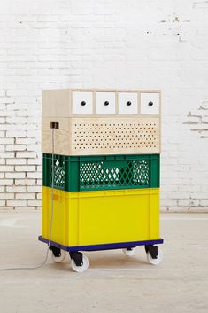 a yellow and green cart sitting in front of a white brick wall with drawers on it