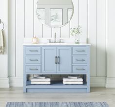 a blue bathroom vanity with mirror and towels on the counter next to it, in front of a white wall