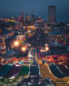 an aerial view of a carnival at night with lights on and rides in the background