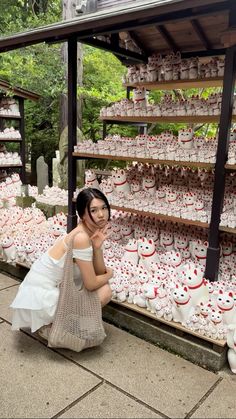 a woman kneeling down in front of a display of cupcakes