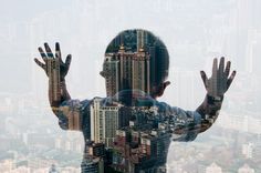 a man standing in front of a city skyline with his hands up to the sky