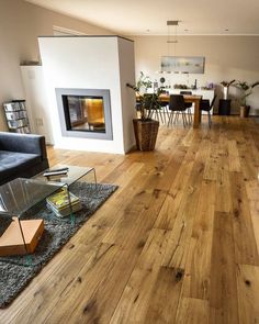 a living room filled with furniture and a fire place next to a table on top of a hard wood floor