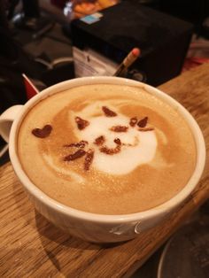 a cappuccino in a white cup on top of a wooden table