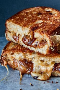 two grilled cheese sandwiches stacked on top of each other in front of a blue background