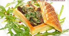 a pastry with meat and vegetables on it sitting on top of a green leafy salad