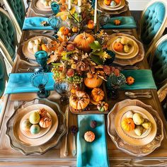 a dining room table is set with blue and gold place settings, pumpkins on the plates