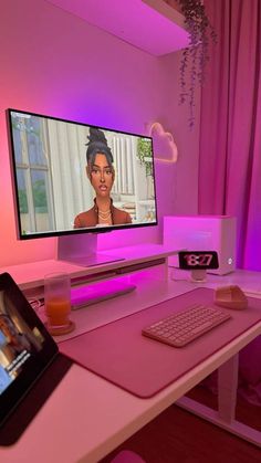 a desk with a computer monitor, keyboard and mouse on it in front of a pink wall