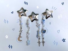 three star and moon earrings hanging from hooks on a wall with stars and crescents