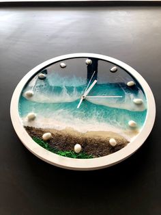 a clock that is on the side of a table with water and rocks in it