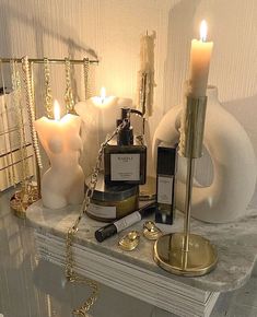 candles, perfume bottles and other items are sitting on a shelf in front of a mirror