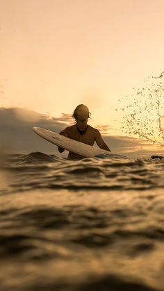 a man standing in the ocean holding a surfboard