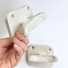 a hand holding a white object next to it's holder