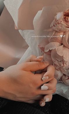 a woman's hands with white manicures holding a bouquet of pink flowers