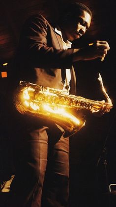 a man standing in front of a microphone holding a saxophone