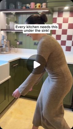 a woman in a bathrobe is dancing around the kitchen counter top and sink