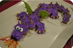 purple cupcakes with sprinkles and decorations on a white platter