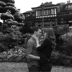 a man and woman standing next to each other in front of a house