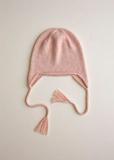 a pink knitted hat with tassels on top