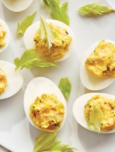 several deviled eggs on a white plate with lettuce and garnish