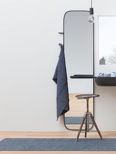 a bathroom with a stool, mirror and towel rack