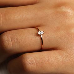 a woman's hand with a diamond ring on top of her left hand,