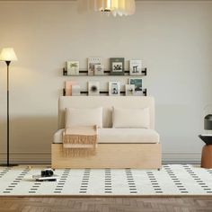 a white couch sitting on top of a wooden floor next to a lamp and pictures