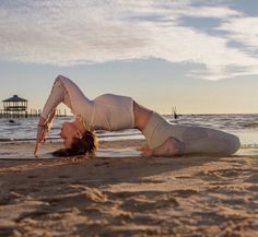 a woman is doing yoga on the beach