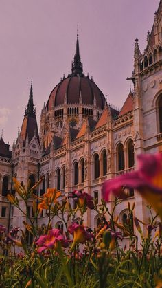 flowers in front of an ornate building with steeples and domes on the top floor