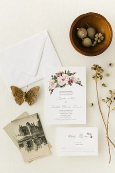 the wedding stationery is laid out on top of the table with flowers and an envelope