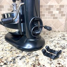 a black blender sitting on top of a counter next to two pieces of metal