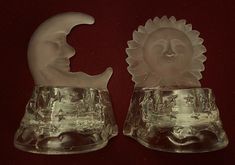 two glass candlesticks sitting on top of a red cloth covered table next to each other