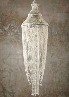 a white chandelier hanging from the ceiling in a room with concrete walls and flooring