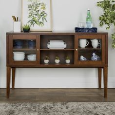 a wooden shelf with plates and cups on it in front of a wall mounted plant