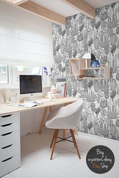 a desk with a computer on top of it in front of a wallpapered background