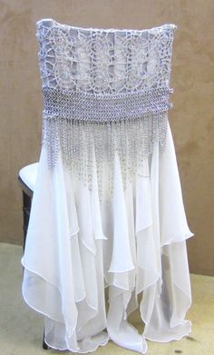 the back of a white chair with beaded trimmings and ruffled skirt