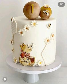 a winnie the pooh themed cake with two apples on top and daisies around it