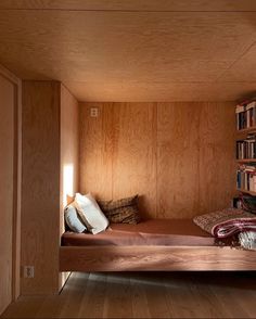 a bed in a room with bookshelves on the wall and wooden flooring