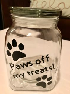 a glass jar with paw prints on it and the words paws off my treats in black ink