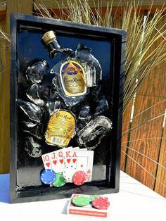 a display case with playing cards and liquor bottles in it on a white table cloth