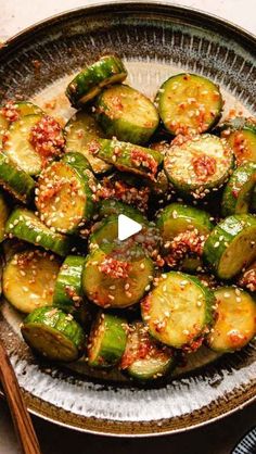 a bowl filled with sliced up cucumbers covered in sesame seeds and seasoning