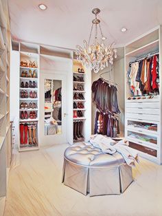 a walk in closet with chandelier and shoes on the floor, all white